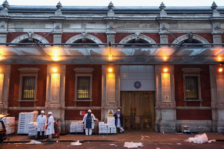 some people are standing in front of a building with boxes on the ground and lights above them