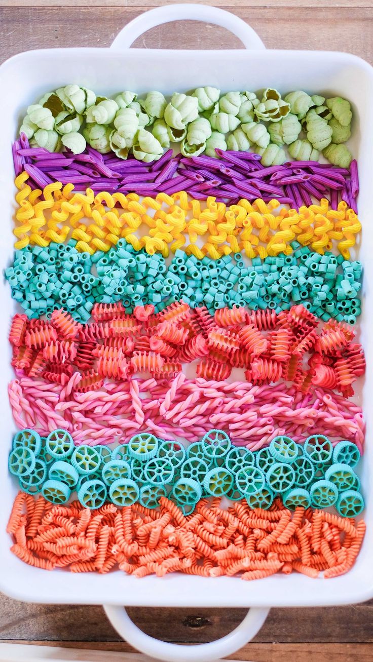 a white dish filled with lots of different colored pasta noodles in it's center