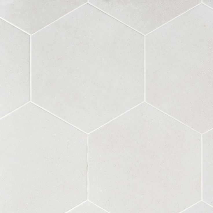 a white tile floor with hexagonal tiles in the middle and one corner missing