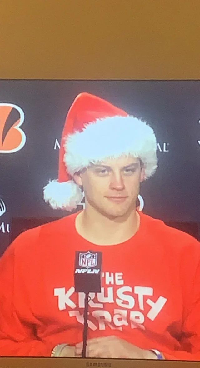 a young man wearing a santa hat on top of a tv screen in front of a microphone