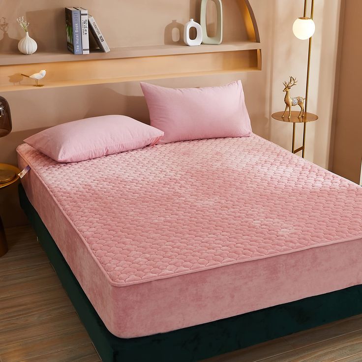 a bed with pink sheets and pillows in a room next to a book shelf filled with books