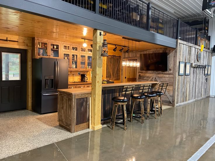 a large kitchen with wooden cabinets and bar stools in the middle of an open floor plan