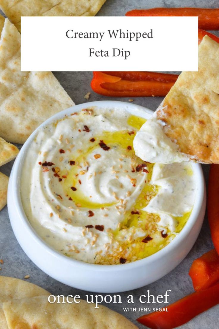 creamy whipped feta dip in a white bowl surrounded by crackers and carrots