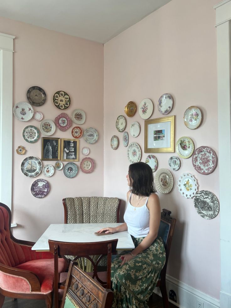 a woman sitting at a table with plates on the wall