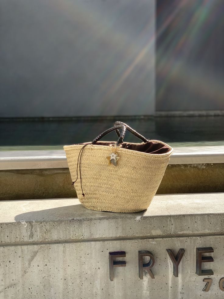 The Brigitte bag is our very modern version of the traditional Panier basket. The basket, handmade by artisans in Spain in palm leaf straw, is covered in a metallic gold mesh, and the short handles coiled in brown leather. It is lined in dark brown cotton fabric, with leather drawstring with metal star charms. The bag is finished with a Cuckoo B keychain featuring a buffalo horn star made in Vietnam, a handmade in Argentina ceramic white star and the Cuckoo B bronze tag. It is inspired on Summer Luxury Straw Tote Bag With Rolled Handles, Luxury Natural Straw Bag For Shopping, Luxury Leather Basket Bucket Bag, Chic Gold Straw Bag, Luxury Natural Straw Bag For Vacation, Luxury Beige Basket Bucket Bag, Brown Top Handle Bucket Bag In Jute, Luxury Straw Bucket Bag With Woven Leather, Luxury Woven Leather Straw Bucket Bag