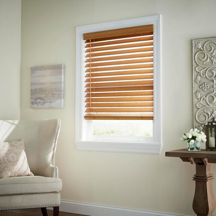 a white chair sitting in front of a window with wooden blinds on top of it