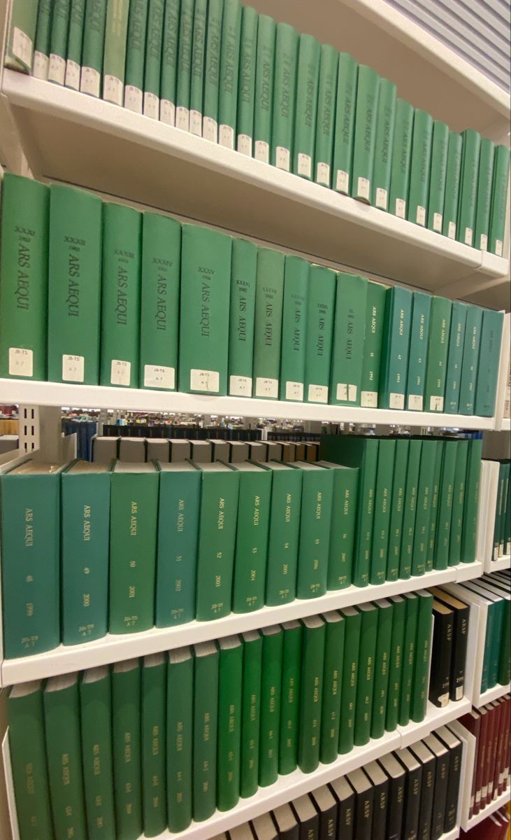 several rows of green books are on the shelves in a book store with white shelving