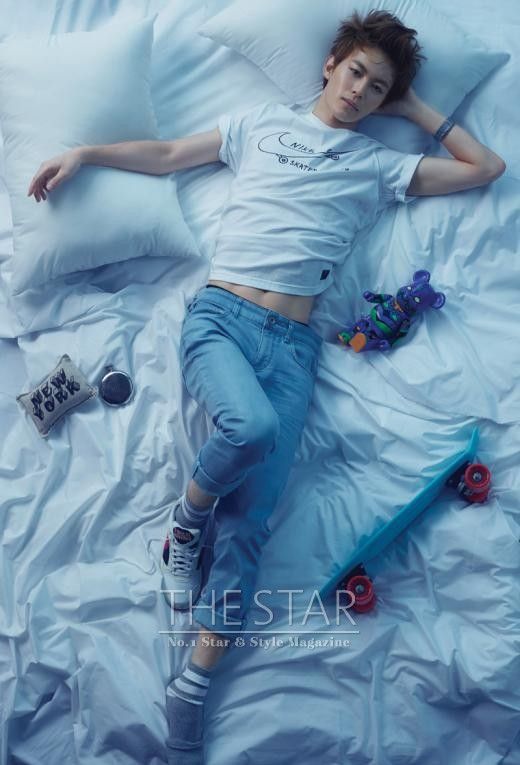 a young man laying on top of a bed next to pillows