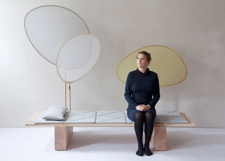 a woman is sitting on a bench in front of a mirror and light bulb lamp