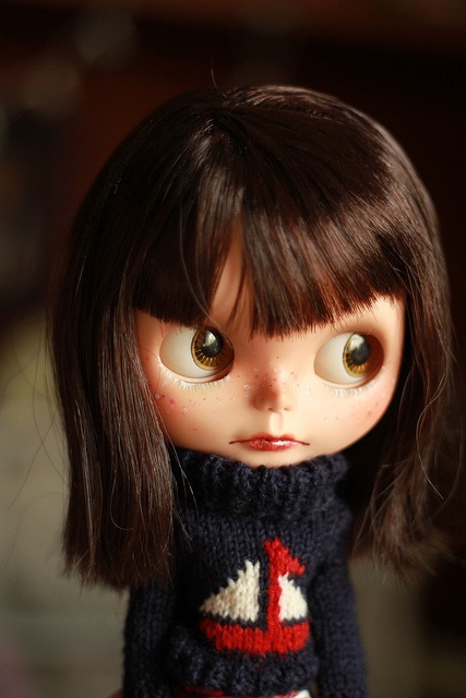 a close up of a doll wearing a sweater