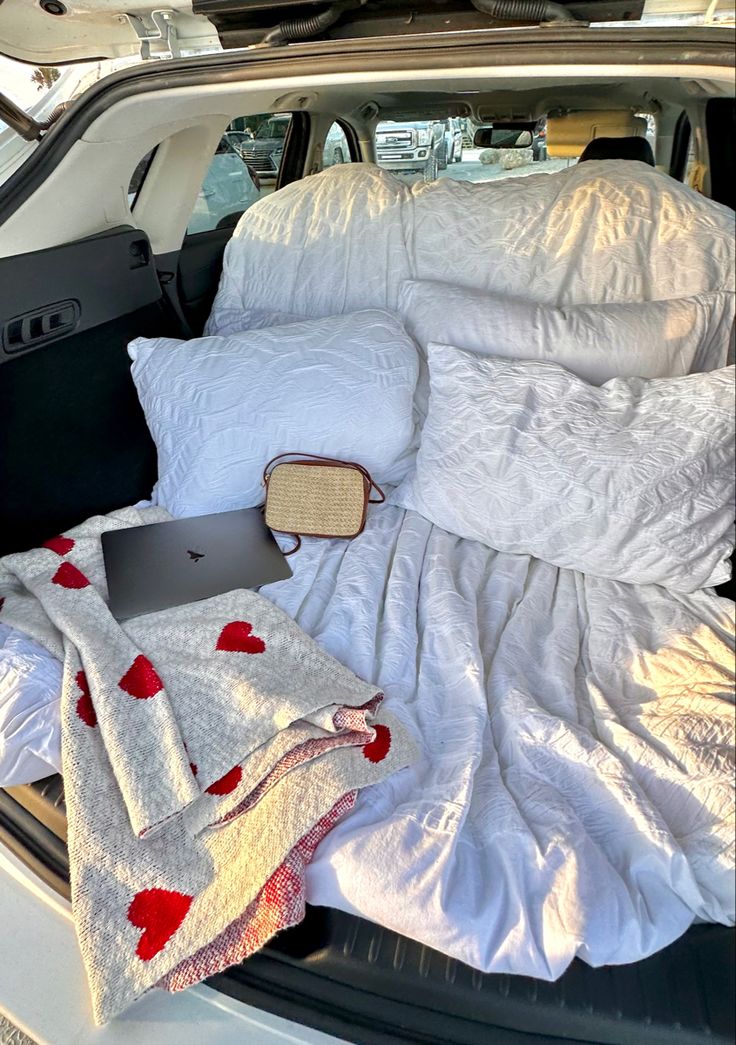 an open car trunk filled with blankets and pillows