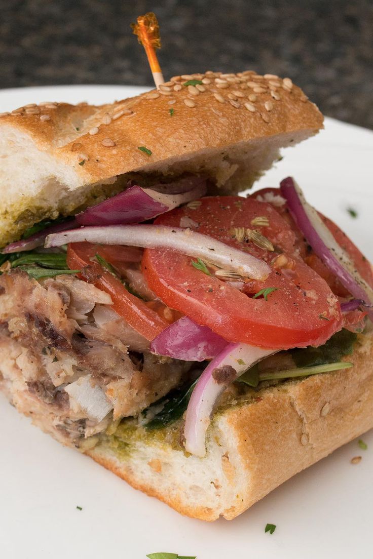 a close up of a sandwich on a plate with tomatoes, onions and lettuce