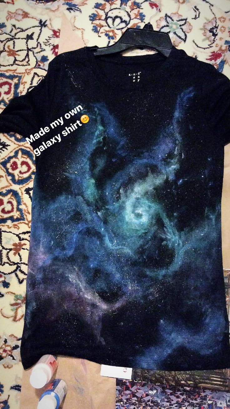 a t - shirt with an image of the stars and galaxy on it is laying on a bed