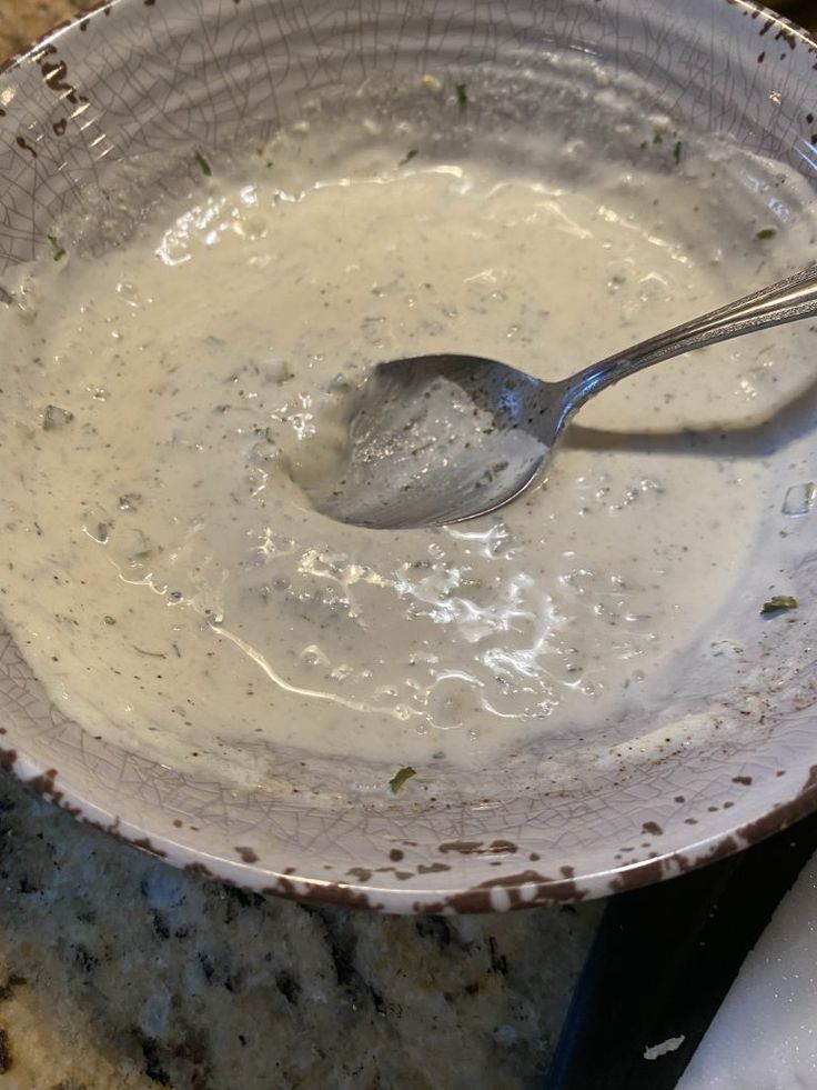 a spoon in a bowl filled with white sauce