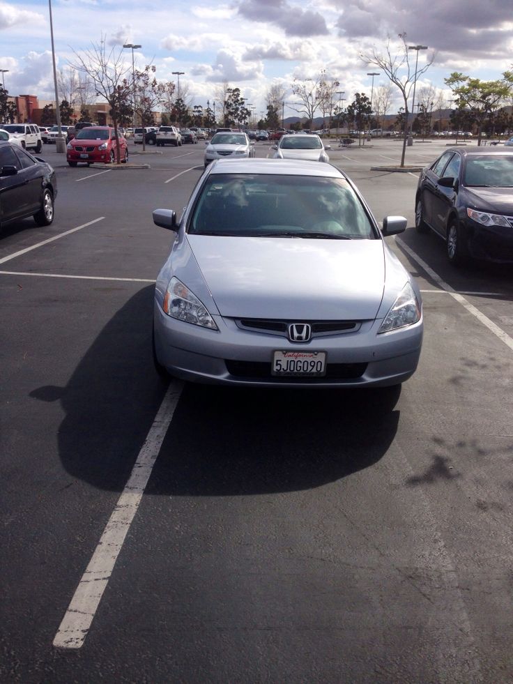 a silver car parked in a parking lot next to other cars on the side of the road