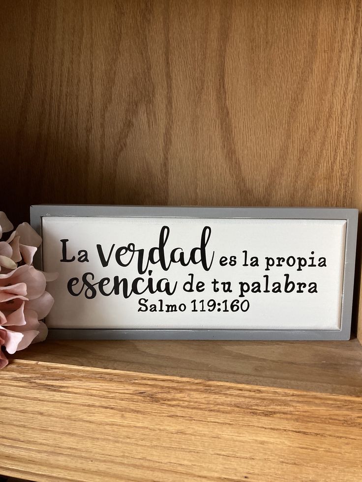 a wooden shelf with flowers and a sign