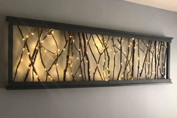 a metal wall art with lights on it in a room next to a bed and window