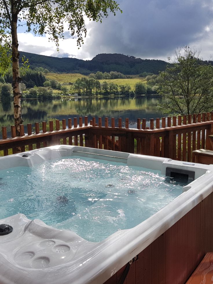 a hot tub sitting on top of a wooden deck next to a body of water