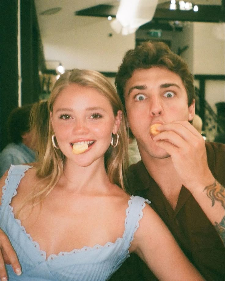 a man and woman are posing for a photo together with food in their mouth,