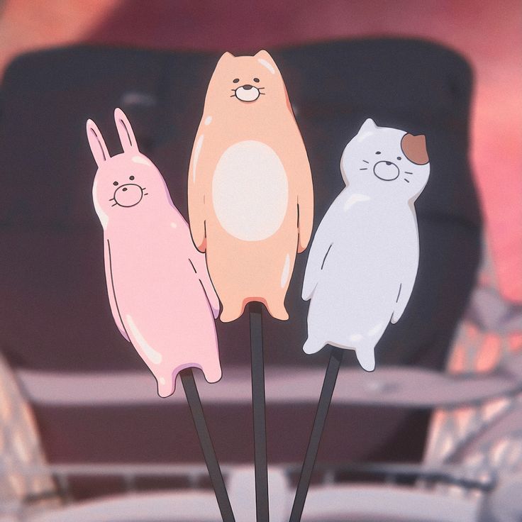 three cat and bunny shaped cake toppers sitting on sticks in front of a chair