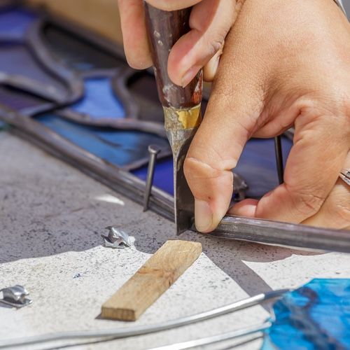 a person working on some metal parts with a pair of scissors in their hand and another piece of wood next to them