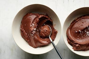 two bowls filled with chocolate frosting on top of a table