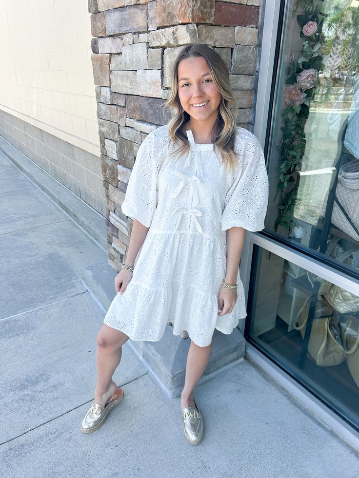 Add a touch of elegance to your wardrobe with the Chic Moment Eyelit Bow Tier Dress in white. This dress features delicate eyelit detailing and a charming bow, making it the perfect choice for any occasion. You'll feel confident and lovely in this stylish and sophisticated piece! Ashlyn is wearing a size small, which is her typical size for dresses! Feminine Eyelet Dresses For Daywear, Elegant Eyelet Dresses For Day Out, White Eyelet Dress For Spring, White Casual Eyelet Dress, White Eyelet Dress For Day Out, White Eyelet Mini Dress Feminine Style, Feminine Eyelet Mini Dress, Feminine Eyelet Dress For Day Out, White Eyelet Dress For Brunch