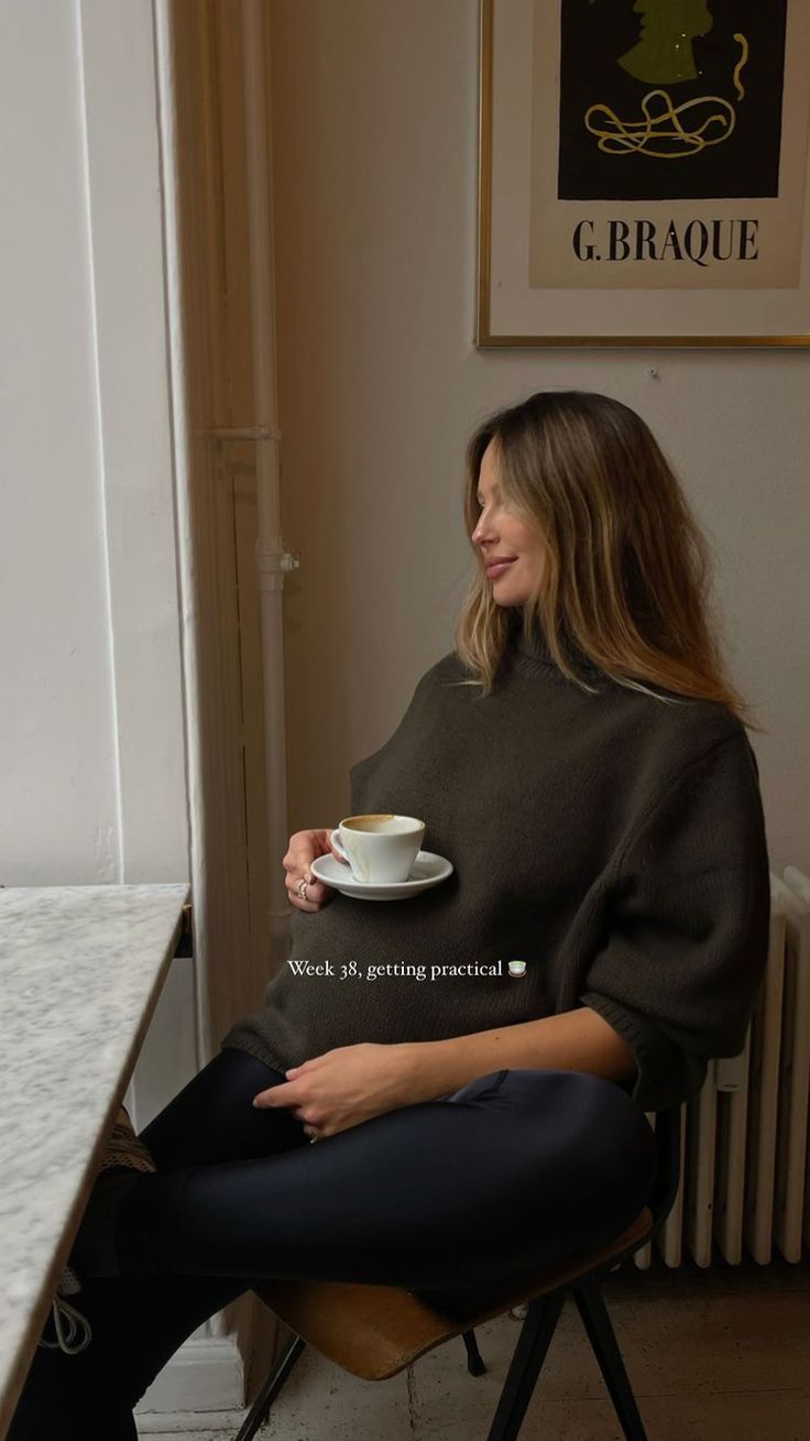 a woman sitting at a table with a cup of coffee