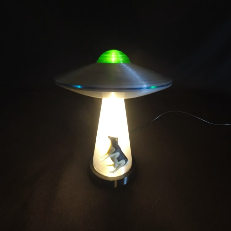 a green and white light sitting on top of a black table next to a lamp