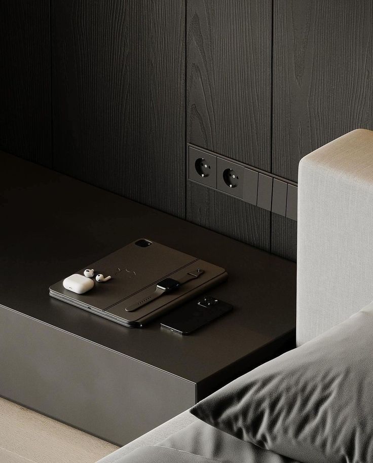 a phone on a table next to a bed with sheets and pillows in front of it