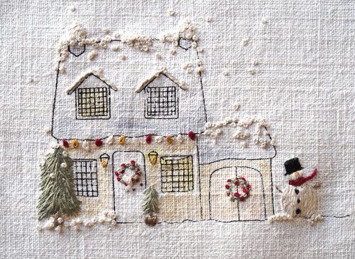 two embroidered houses with snowmen and wreaths on the outside, one in front of the other