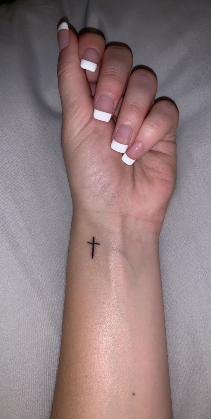 a woman's arm with a cross tattoo on it