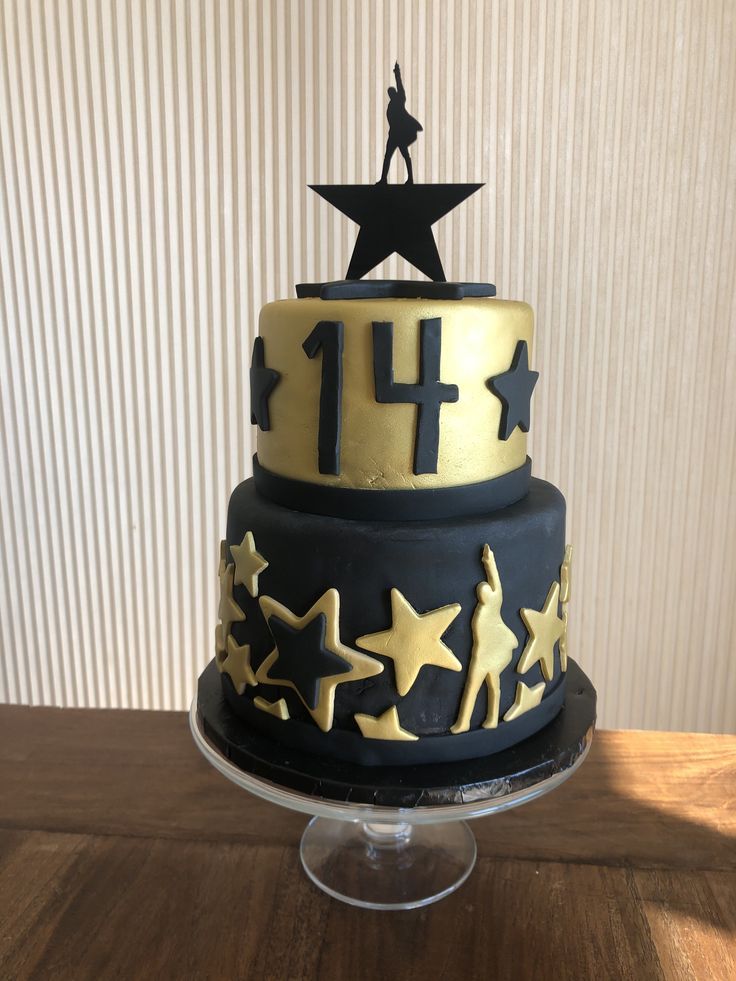 a three tiered cake with gold stars on it and a man standing on top