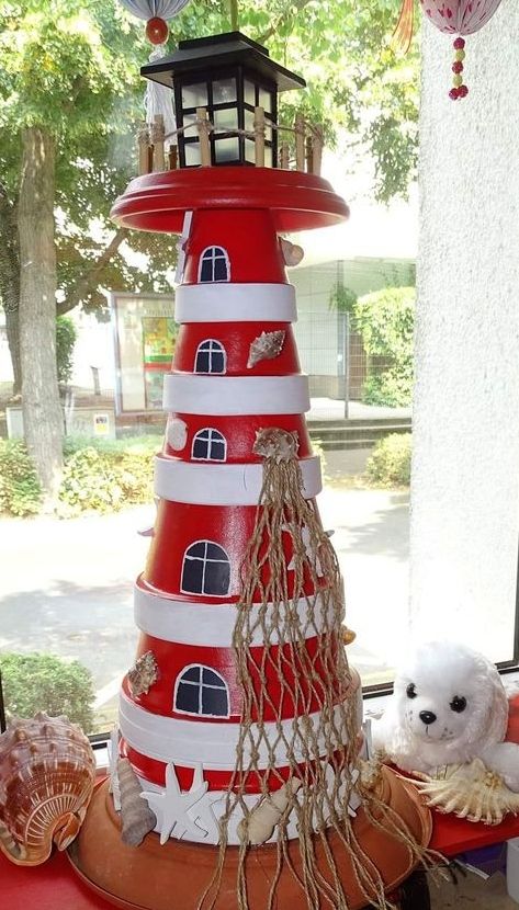 there is a red and white lighthouse on the window sill next to a teddy bear