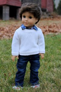 a doll is standing in the grass wearing jeans and a sweater with a bow tie