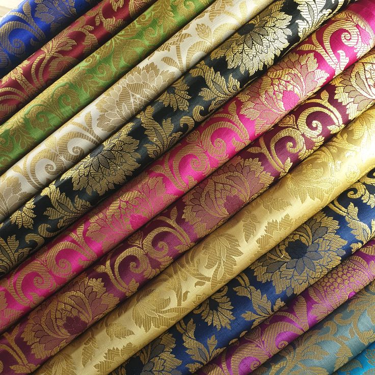 a pile of different colored fabric with gold and blue designs on the sides, all lined up in rows