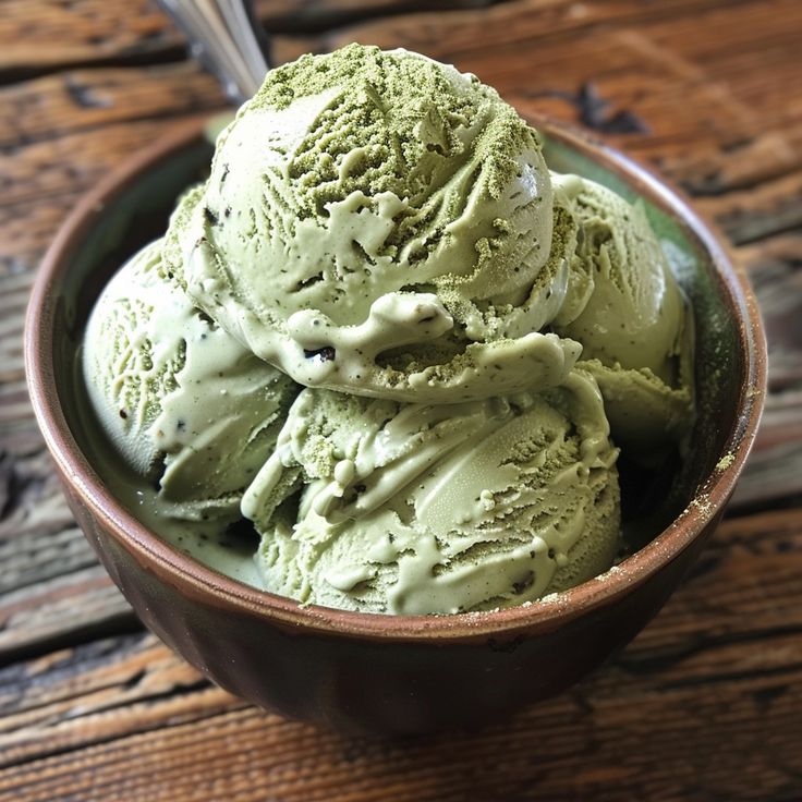 a bowl filled with green ice cream on top of a wooden table