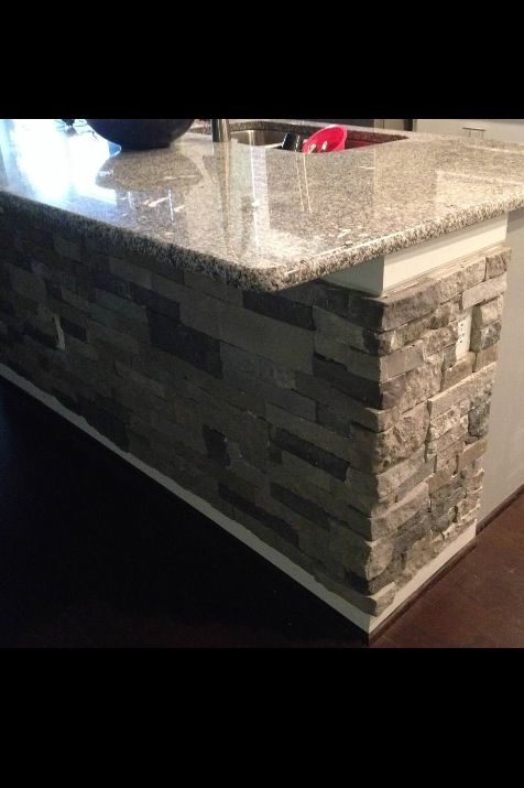 a kitchen island with granite counter tops and white cabinets in the background, next to a sink