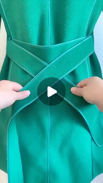 two hands pulling on the back of a green dress