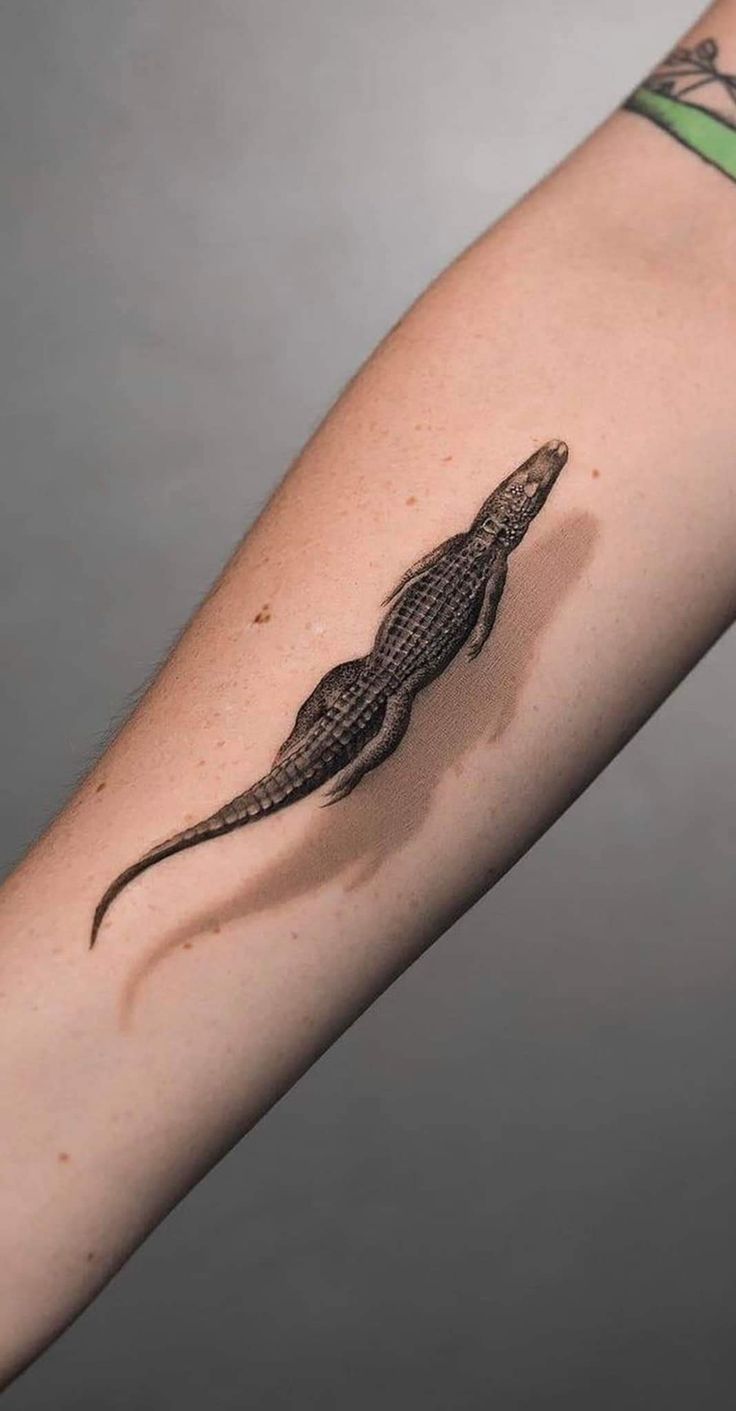 an arm with a lizard tattoo on it