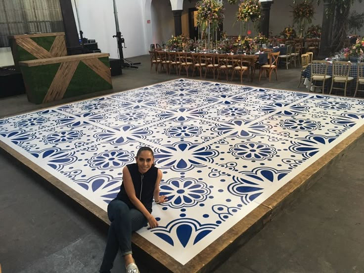 a woman sitting on top of a large blue and white tile covered floor in a room