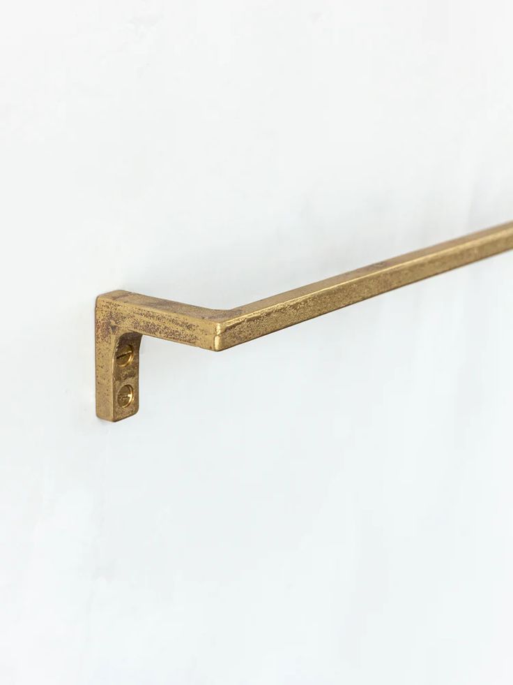 an old brass metal shelf handle on a white wall with no one in the photo