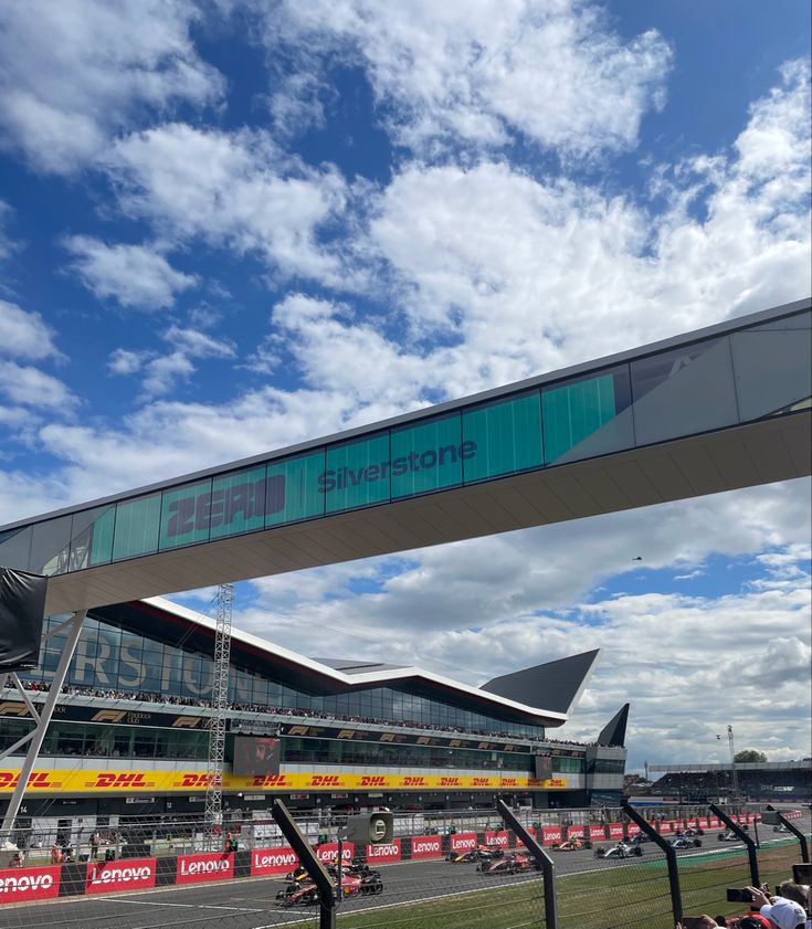 the race track is under a blue sky with white clouds and some people sitting on it