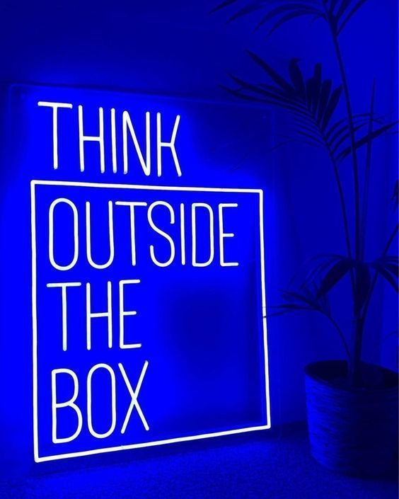 a neon sign that says think outside the box in front of a potted plant