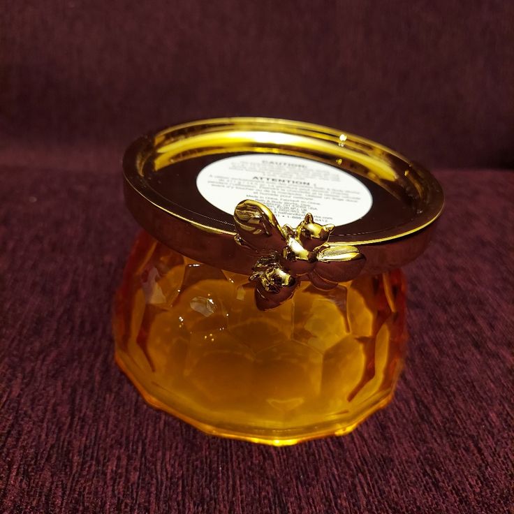 a glass jar with a gold lid on a purple surface