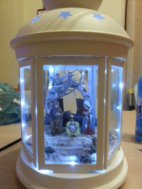 a lighted up lantern with nativity scene in it