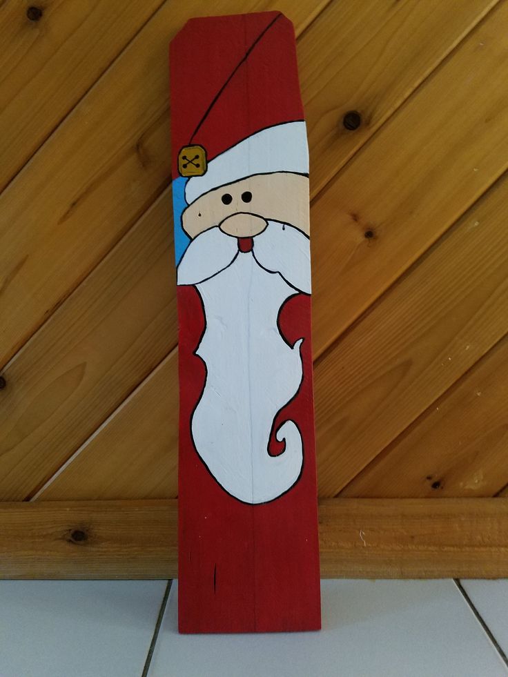 a santa clause painted on top of a skateboard in front of a wooden wall