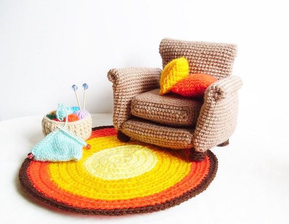 a crocheted rug on the floor with a chair next to it