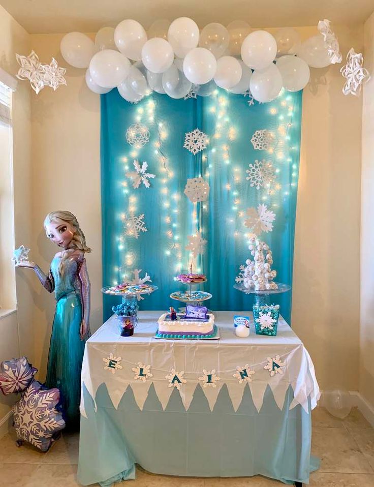 a frozen princess themed birthday party with balloons and streamers on the wall, table