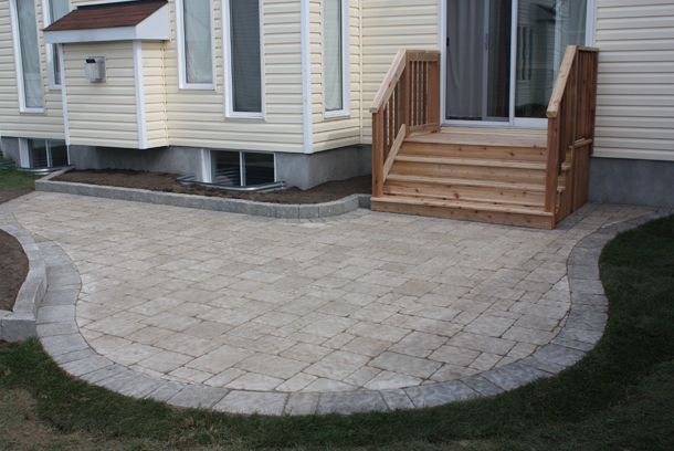 a brick patio with steps leading up to the front door and side of a house